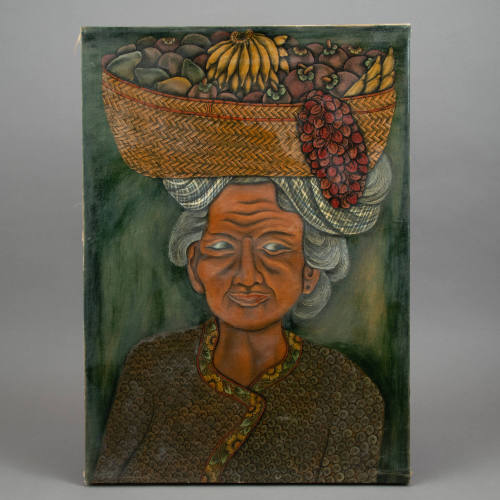 Portrait of a woman carrying a basket of fruit on her head.
