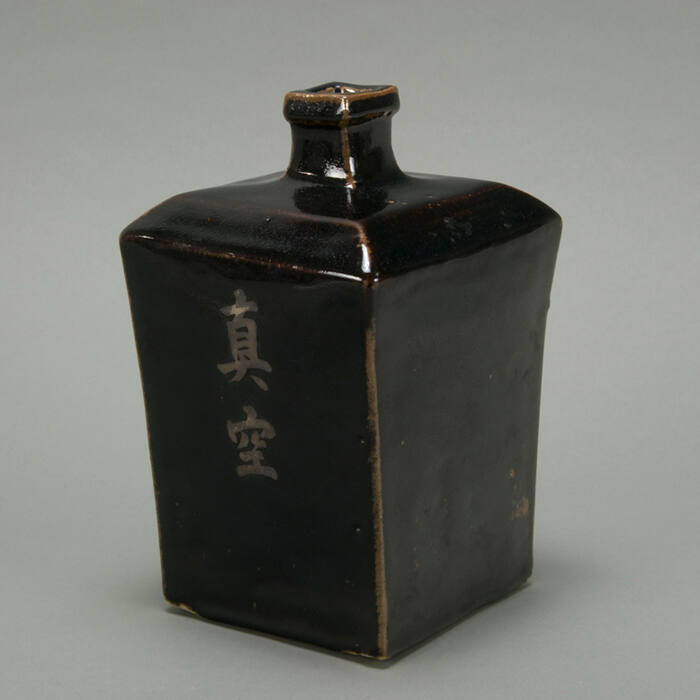 Black square vase with letters.