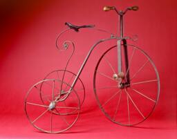 Antique French tricycle of wrought iron with wooden pedal and handle bars; rusty iron; iron, wo…